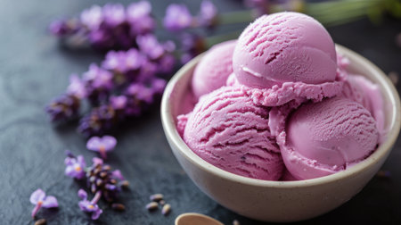 A bowl filled with pink ice cream sits next to lavender flowers in a vibrant and colorful display.の素材