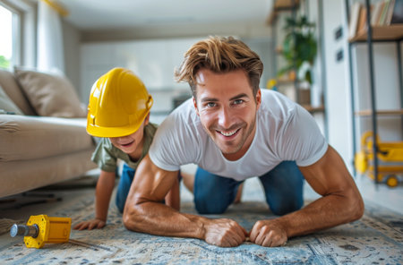 A father and his son are actively working together to install a wooden floor in a home.の素材