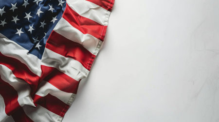 An American flag is laid out on a clean white surface, showing its vibrant red, white, and blue colors.の素材