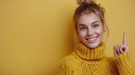 A close-up portrait of a smiling woman with long brown hair wearing a yellow knitted sweater in front of a yellow wall.の素材