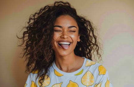 A close-up portrait of a young woman with curly hair, smiling and sticking out her tongue.の素材