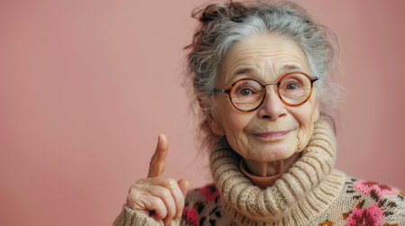 An older woman, wearing glasses and a pink sweater, is gesturing the peace sign with her fingers in a casual pose.の素材