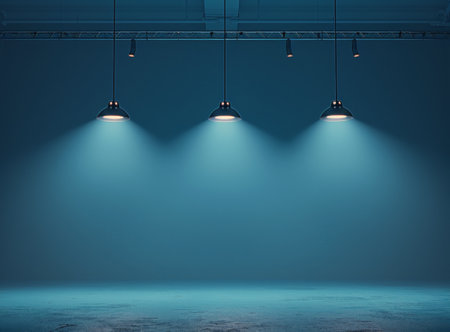 Three spotlights hang from a ceiling, illuminating a large, empty studio space with a blue wall and floor.の素材