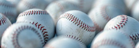 A close-up view of multiple baseballs, all slightly worn, piled on top of each other.の素材