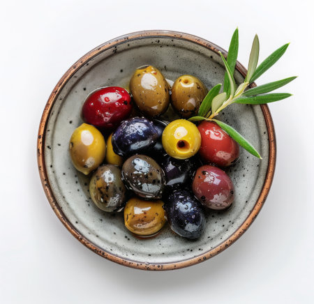 A small, green ceramic bowl filled with green olives in brine.の素材