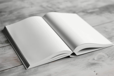 A white book is open, lying flat on a gray surface. The book is open to a blank page.の素材
