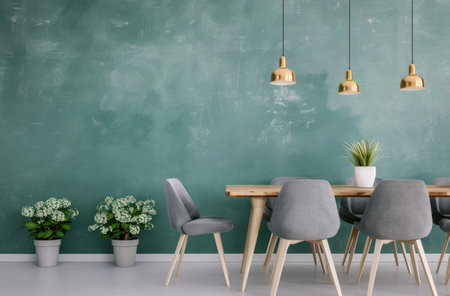 A gray sofa with pillows sits in front of a teal wall with four gold pendant lights. Two potted plants add a touch of green.の素材