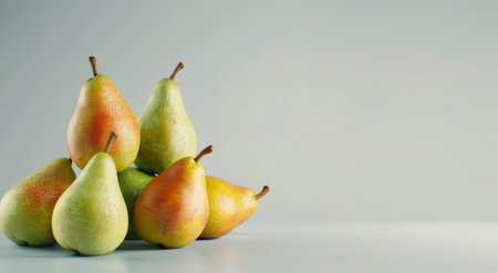 A collection of ripe green pears arranged in a pyramid on a smooth surface, showing their vibrant skin texture and natural shape against a light-colored backdrop.の素材