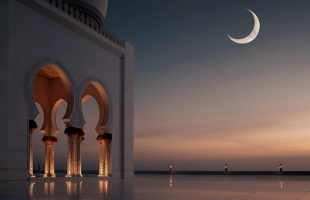 Elegant archways of a mosque are illuminated as the crescent moon hangs in a twilight sky, creating a serene atmosphere at dusk by the coastline.の素材
