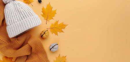 A warm white beanie, a soft scarf, decorative pumpkins, and autumn leaves are arranged on a vibrant yellow background, capturing the essence of fall fashion and seasonal spirit.の素材