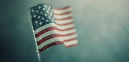 An American flag flutters proudly in the foreground while a sea of people gathers in the background during an evening event, illuminated by soft lights that reflect patriotism and unity.の素材
