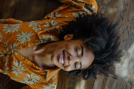 A woman in a brown floral shirt is depicted lying on the floor in a casual and relaxed pose. She appears to be deep in thought or taking a moment of rest.の素材