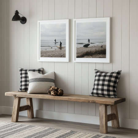A well-decorated living space featuring two framed beach art pieces on white walls, a wooden bench with plaid cushions, and potted greenery, creating a serene atmosphere.の素材