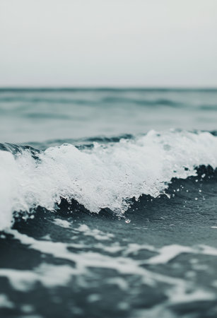 Soft waves wash onto the sandy beach as the sun sets, painting the sky in shades of pink and orange while creating a peaceful atmosphere.の素材
