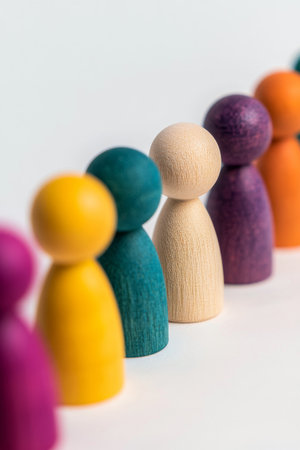 A series of colorful wooden figures stands in a straight line against a neutral background. Each figure features unique designs and vibrant colors, creating an inviting visual contrast.の素材
