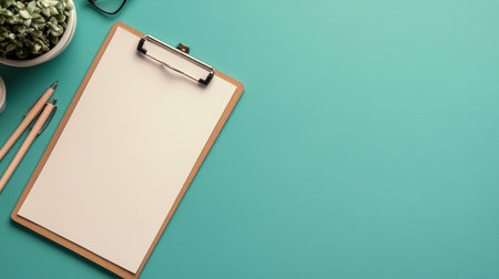 A well-organized workspace featuring a blank clipboard, two pens, a pair of glasses, and a small potted plant, all set against a vibrant turquoise surface, creating a refreshing atmosphere.の素材