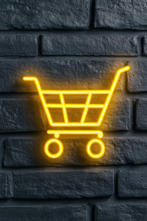 A vivid neon shopping cart symbol illuminates a dark, textured brick wall, creating a lively urban atmosphere. The bright orange light contrasts with the cool tones of the wall.の素材