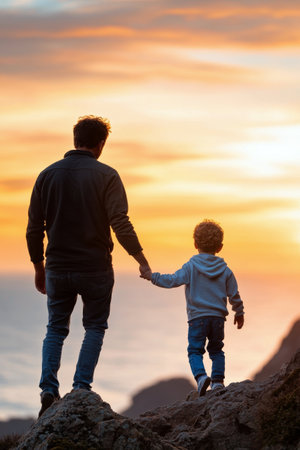 A father and his young son stroll along a rugged coastline, holding hands as the vibrant sunset paints the sky. They embrace the beauty of nature and share a cherished moment.の素材