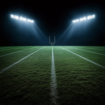 The bright lights of a stadium shine down on a perfectly manicured football field, creating a captivating ambiance under the night skyの素材