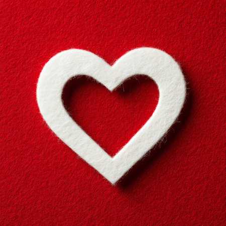 A white felt heart cutout lays on a rich red surface, creating a striking contrast. The simplicity of the design highlights the love theme effectively.の素材