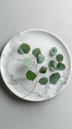 Fresh eucalyptus branches are thoughtfully placed on a marble plate, creating a calming atmosphere in a cozy indoor space, showing the beauty of natural elements.の素材