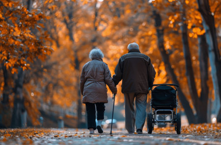 An elderly couple walks hand-in-hand through an autumn forest, with a man pushing a stroller.の素材