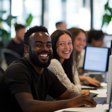 A group of smiling professionals collaborated in a bright office space filled with greenery. They are engaged in work on their laptops, creating a vibrant and supportive atmosphere.の素材
