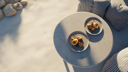 A serene beachside setting features a round table with two plates filled with pastries. The golden morning light casts a warm glow on the sand, creating a peaceful atmosphere.の素材