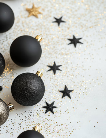 Gold and black Christmas ornaments are arranged creatively against a white background, sprinkled with golden stars and glitter, creating an elegant festive atmosphere for the holidays.の素材