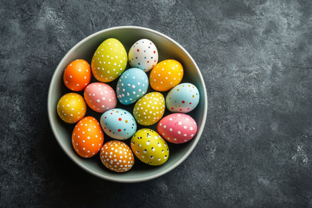 A bowl filled with vibrant, decorated eggs in various colors and patterns sits on a textured surface. These eggs are ready for a spring celebration, showcasing creativity and festivity.の素材