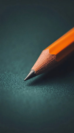 A sharpened yellow pencil is positioned on a dark surface, emphasizing its fine point and inviting creativity. This setup creates a perfect atmosphere for writing or drawing.の素材