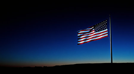 The American flag flutters gracefully against a dark background, showing vibrant colors and textures. Each star and stripe is clearly visible, representing unity and freedom.の素材