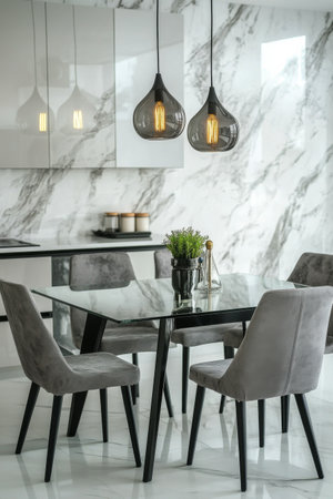 A modern dining area showcases a glass-top table with a unique black base surrounded by stylish chairs. Pendant lights hang above, adding a touch of elegance to the sleek design.の素材