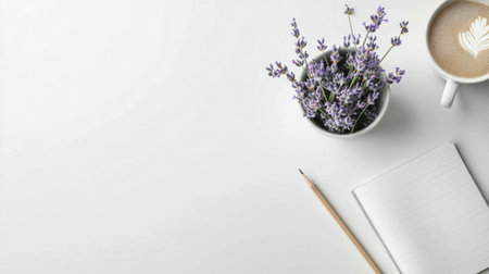 A small pot of blooming lavender sits next to a cup of coffee with latte art. Nearby, a blank notepad and a pencil are placed on a minimalist white desk, creating a serene environment.の素材
