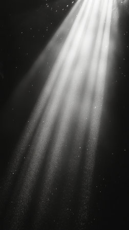 Brilliant shafts of light filter through an opening above, illuminating suspended particles in a deep, dark underwater setting. The contrast creates a mesmerizing effect.の素材
