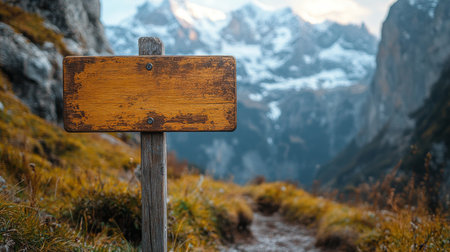 A weathered wooden signpost stands at the edge of a mountain trail, surrounded by breathtaking views of snow-capped peaks and golden autumn foliage at sunset.の素材