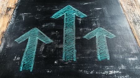 Three arrows in chalk point upwards on a blackboard, symbolizing growth and progress. The vibrant green stands out against the dark background, emphasizing positivity.の素材