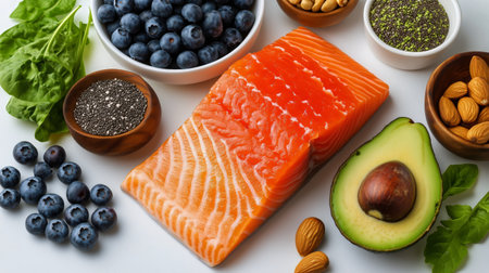 Colorful bowls filled with blueberries, nuts, and greens surround salmon and avocado, showing a vibrant array of healthy foods ready for meal prep or cooking.の素材