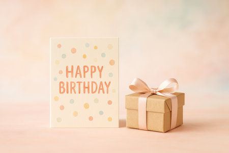 A birthday card with cheerful writing sits next to a small gift box wrapped in ribbon, creating a festive atmosphere perfect for celebrating.の素材