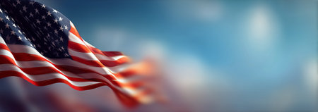 The American flag flutters energetically in the wind, showing vibrant colors of red, white, and blue against a bright blue sky during daylight hours.の素材