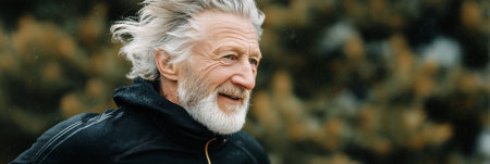 An older man with gray hair and a beard runs joyfully through a park during the morning. The lush surroundings and warm sunlight create a serene atmosphere for his activity.の素材