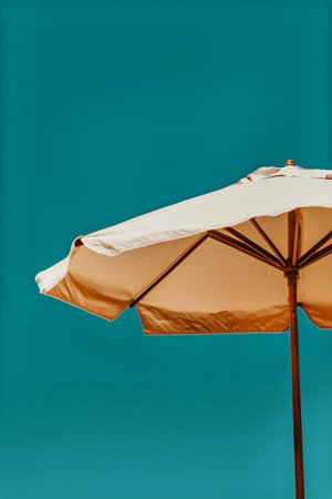 A large yellow umbrella stands tall on a sandy beach under a bright blue sky. The scene captures a serene day perfect for sunbathing and relaxation.の素材