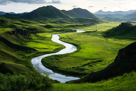 A winding river flows through a vibrant green valley surrounded by mountains. The sun sets, casting golden light on the landscape, highlighting the natural beauty of the area.の素材