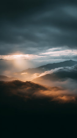 Majestic mountains rise dramatically above a sea of clouds during sunrise, with soft golden light casting shadows. A tranquil and serene moment displaying natures beauty.の素材