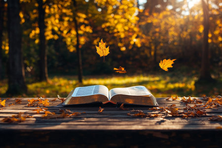 A book lies open on a rustic wooden table surrounded by fallen leaves in a colorful autumn forest during sunset. Leaves are gently falling, creating a serene atmosphere..の素材