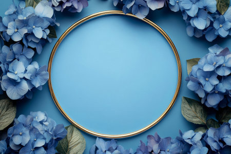 Delicate white hydrangeas surround a circular frame, creating a stunning display on a bright blue surface. The arrangement highlights the fresh blooms and vibrant colors.の素材