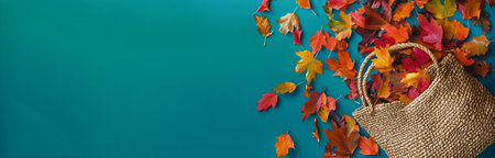 A woven basket overflows with vibrant autumn leaves in shades of red, orange, and yellow, resting on a bright turquoise background, showing seasonal beauty and texture.の素材