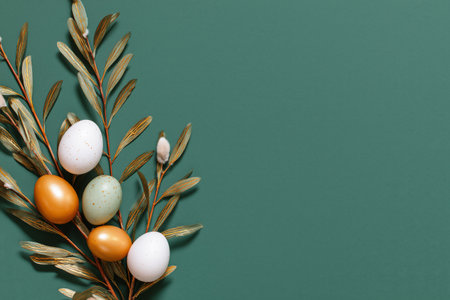 Five decorative eggs in various colors are gently placed among soft willow branches against a green backdrop, creating a festive Easter atmosphere..の素材