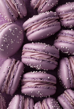 Soft lavender macarons filled with creamy frosting and adorned with white sugar pearls create an inviting dessert display. Perfect for celebrations or gatherings..の素材