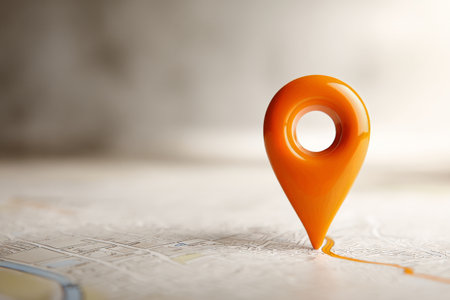 A bright orange location pin sits on a detailed map, pointing to a specific area. The pin appears glossy and reflects light, drawing attention to its position on the map.の素材